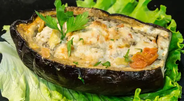 Melanzane ripiene di carne al forno, un piatto gustoso e colorato, servito su un letto di lattuga fresca.