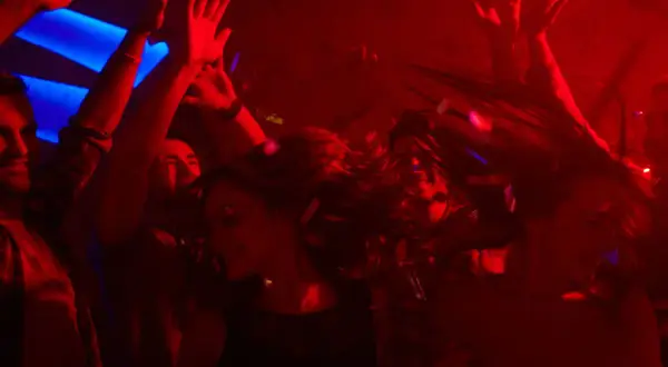 Leute tanzen ausgelassen im Club, die Haare fliegen, Konfetti fällt. Perfekt für eine **2000er Hits playlist**.