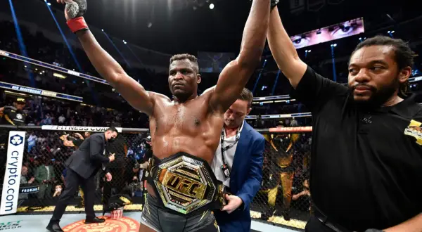 En segerrik UFC-mästare, med bälte och armarna i luften, firar som en riktig sumo brottare.