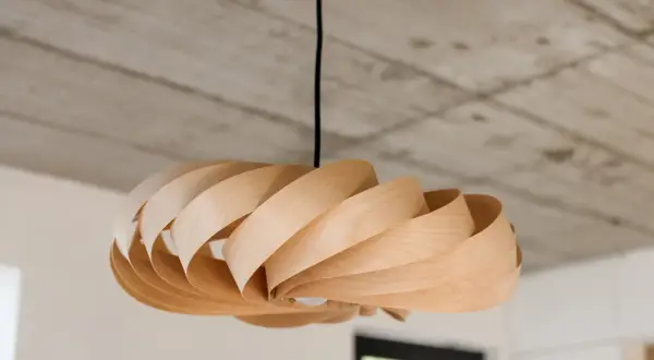 Lampadario in legno fai da te, con lamelle curve che creano un effetto a spirale. Luce soffusa e design naturale.