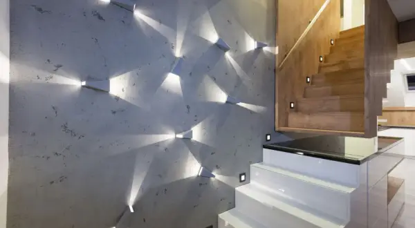 Moderne Wandgestaltung mit geometrischen Spots, die Lichtmuster auf Beton werfen. Perfekte Wand-Inspo für einen stilvollen Treppenaufgang.