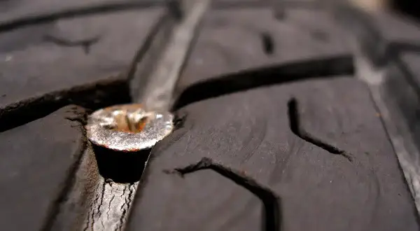 Une mèche est plantée dans le pneu d'une voiture, causant une crevaison.
