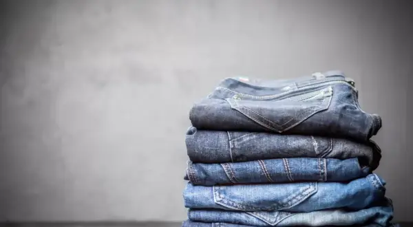 Stosik złożonych jeansów, każdy w innym odcieniu niebieskiego. Z czego jest jeans? Z bawełny, tkanej diagonalnie, co nadaje mu wytrzymałość.