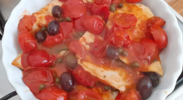 Petto di pollo alla pizzaiola in teglia, con pomodorini, olive nere e capperi. Un piatto saporito e colorato.