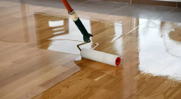 Application d'une couche de vernis pour vitrifier un parquet en bois, lui donnant un aspect brillant et protecteur.