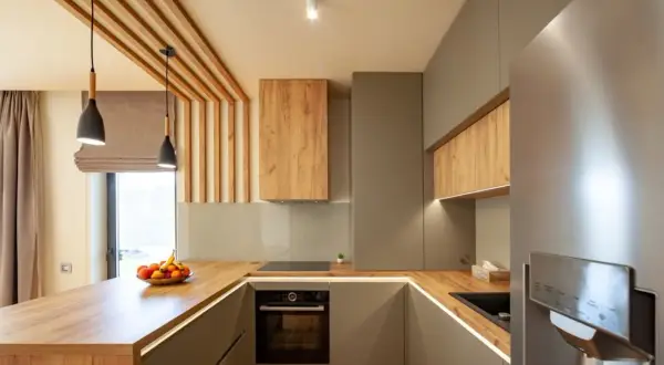 Cuisine moderne avec home staging réussi, mêlant bois chaleureux et finitions grises élégantes. L'îlot central en bois et les suspensions créent une ambiance accueillante.