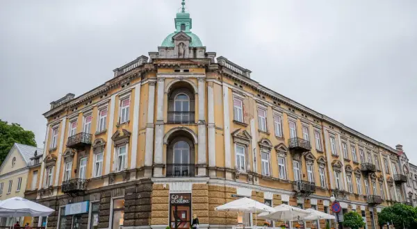 Kamienica w Radomiu z żółtą fasadą, kopułą i kawiarnią na parterze.