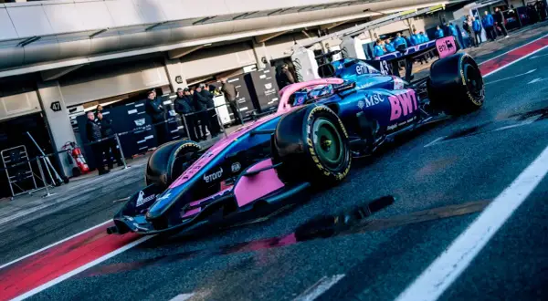Coche de **Alpine F1** azul y rosa listo para la carrera en el pit lane.