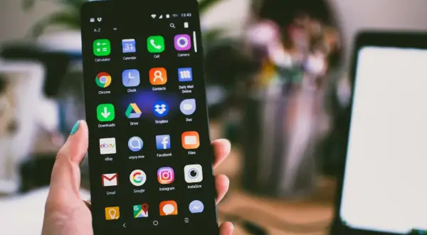 Dłoń trzyma smartfon z widocznym schowkiem w telefonie, pełnym ikon aplikacji, takich jak Gmail, Google i Instagram.