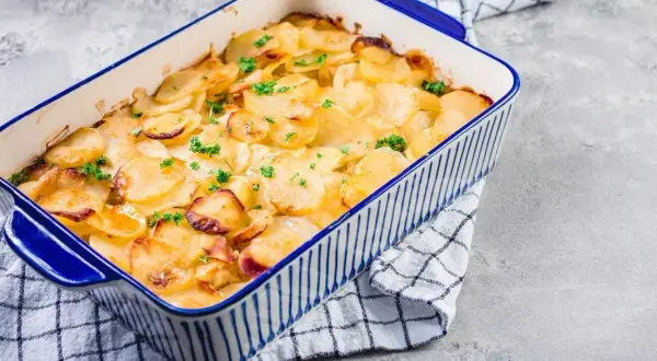 Goldbrauner Kartoffelauflauf mit Petersilie in einer blauen Auflaufform. Ein köstliches Kartoffelauflauf Rezept, das zum Genießen einlädt.