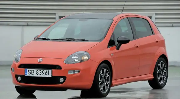 Pomarańczowy Fiat Punto na mokrej nawierzchni. Zwróć uwagę na jego kompaktowe fiat punto wymiary, idealne do miasta.
