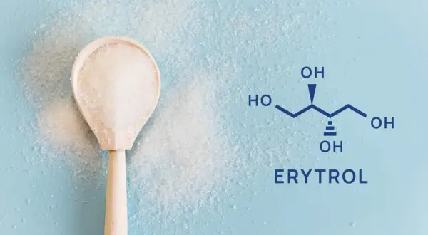 Drewniana łyżka z kryształkami erytrolu obok wzoru chemicznego. Erytrytol to zdrowa alternatywa dla cukru.