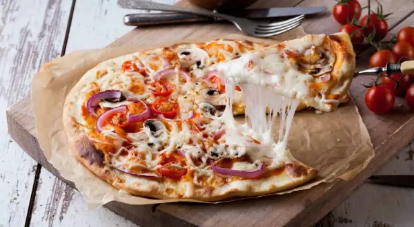 Eine köstliche Pizza mit geschmolzenem Käse, Tomaten, Zwiebeln und Pilzen. Der Teig, wie vom echten Italiener, wurde im Thermomix zubereitet.