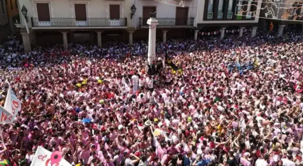 Multitudinaria plaza en las fiestas del Torico de Teruel, con gente vestida de blanco y rosa celebrando.