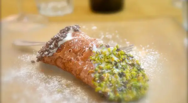 En krispig cannelloni dessert med pistagenötter och chokladströssel, pudrad med florsocker.