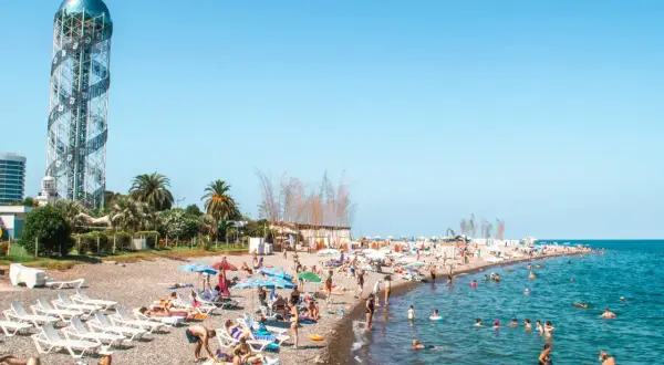 Tłum ludzi na plaży w Batumi, Gruzja. W tle charakterystyczna wieża. Odpowiedź na pytanie: czy w Gruzji jest bezpiecznie? Tak, plaże są pełne turystów.