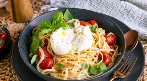 Spaghetti mit Burrata, Kirschtomaten und Basilikum in einer Schüssel.