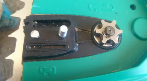 Widok z bliska na mechanizm piły elektrycznej, w tym zębatkę i elementy pompki oleju.