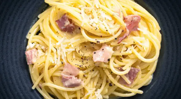 Spaghetti Carbonara mit Speck und Parmesan, ein Gericht, das leicht misslingt. Vermeiden Sie 10 Fehler beim Pasta kochen für perfekten Genuss.