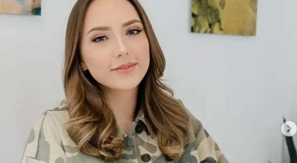 Uśmiechnięta Hailie Jade Scott Mathers w kurtce moro, z lekko pofalowanymi brązowymi włosami.