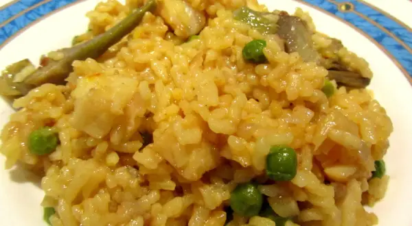 Arroz con bacalao y alcachofas, un plato reconfortante con guisantes verdes y trozos de pescado blanco.