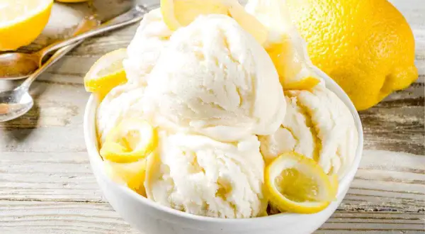 Coppa di cremoso gelato al limone bimby, guarnita con spicchi freschi. Un'esplosione di freschezza estiva.