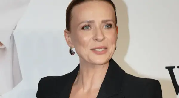 Aneta Zając w czarnej marynarce, z dużymi kolczykami, uśmiecha się. Jej partner, jeśli jest obecny, nie jest widoczny.