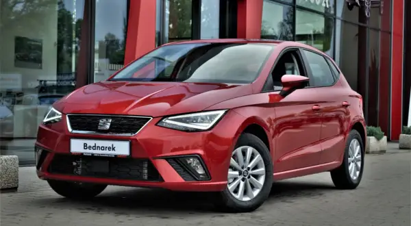 Czerwony SEAT Ibiza, jeden z popularnych modele, zaparkowany przed salonem samochodowym.