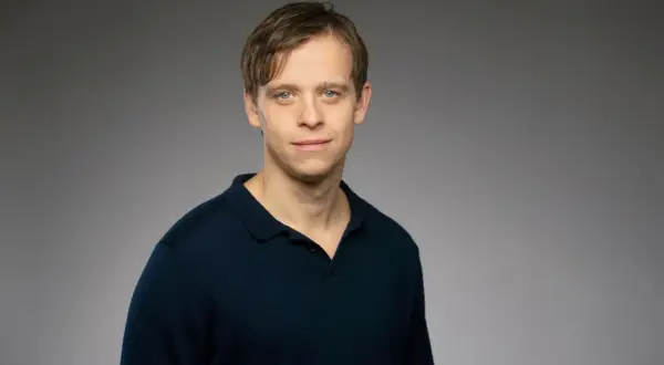 David Pålsson, en ung man med blå ögon och brunt hår, bär en mörkblå pikétröja.