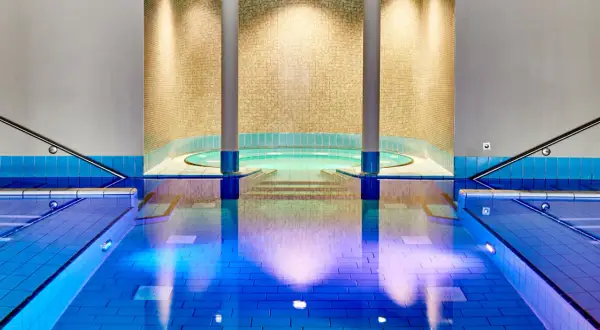 Innenpool mit Whirlpool und blauen Fliesen, beleuchtet.