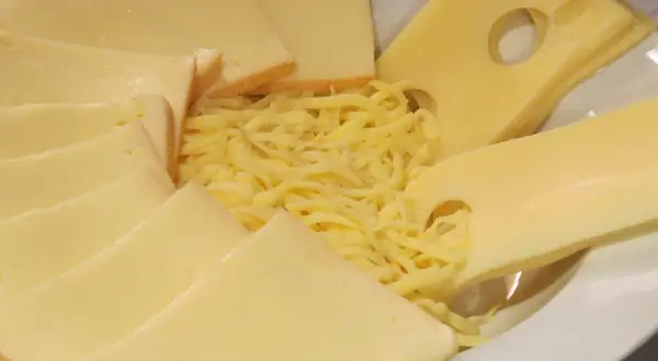 Assiette de fromages variés, dont des tranches d'Emmental avec ses trous caractéristiques, et du Gruyère râpé. La différence entre gruyère et emmental est subtile.