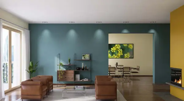 Modernes Wohnzimmer mit zwei Ledersofas, einem Regal und einem Essbereich. Die Wände sind in Petrol und Gelb gestrichen, was zeigt, was ist dispersionsfarbe.
