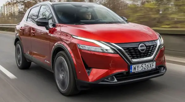 Czerwony Nissan Qashqai 2022 z napędem e-POWER pędzi po drodze, ukazując swoje nowoczesne linie i światła LED.
