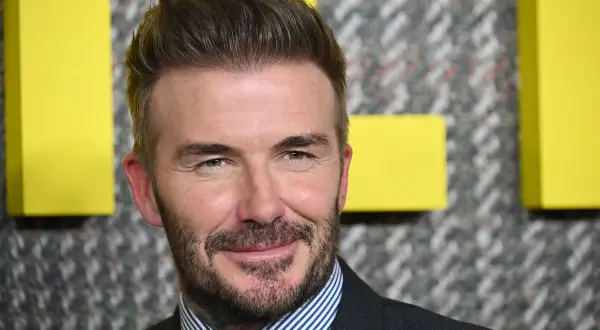 David Beckham sfoggia un taglio corto elegante uomo, con barba curata e un sorriso accattivante.
