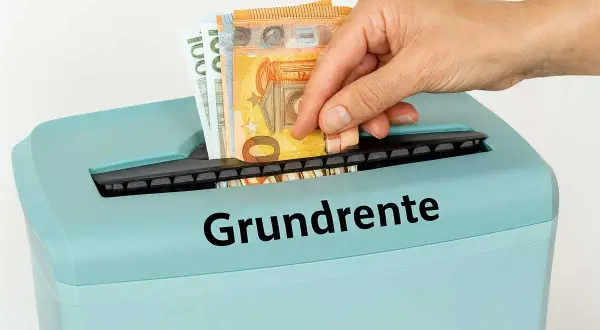 Geld wird in einen Aktenvernichter mit der Aufschrift "Grundrente" gesteckt. Dies symbolisiert die Sorge um die Mindestrente in Deutschland.