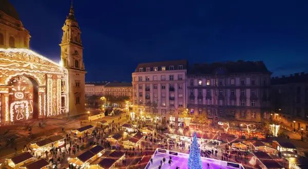 Magiczny budapeszt jarmark bożonarodzeniowy. Tłumy ludzi na lodowisku i przy straganach, oświetlona bazylika w tle.