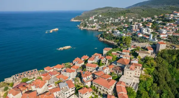Widok na malownicze miasteczko Ulcinj z czerwonymi dachami, otoczone zielonymi wzgórzami i błękitnym morzem. Odkryj atrakcje tego nadmorskiego kurortu.