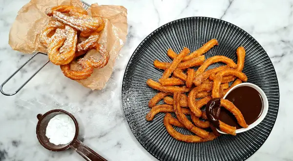 Churros przepis: złociste, chrupiące paluszki posypane cukrem pudrem i cynamonem, podane z gorącą czekoladą. Idealne na deser!