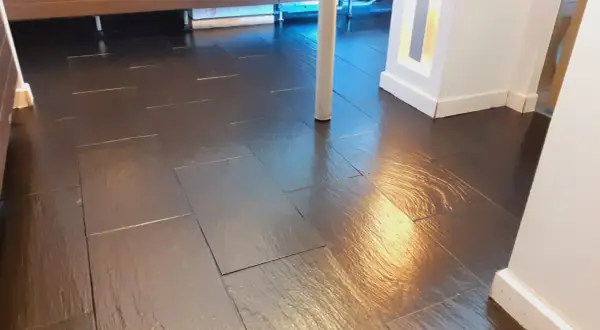 Pavimento in bollettonato di marmo scuro, lucido e riflettente, con un pilastro bianco al centro.