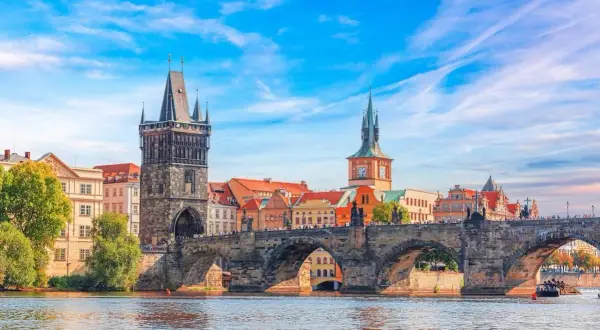 Le pont Charles et la tour de la Vieille Ville, témoins de la riche prague histoire, se reflètent dans la Vltava sous un ciel bleu.