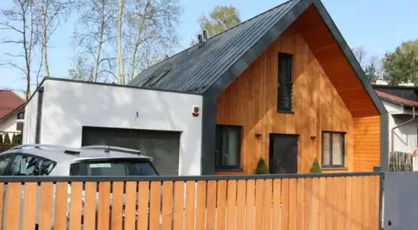 Nowoczesna dobudówka do starego domu, z drewnianą elewacją i garażem. Projekty architektoniczne łączące tradycję z nowoczesnością.
