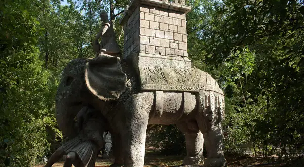 Elefante di pietra con guerriero e torre nel viterbo giardino dei mostri. Un'antica creatura che emerge dal verde.