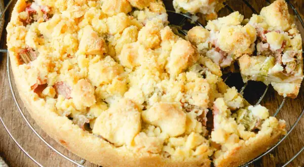 Ein köstlicher Rhabarberkuchen mit Streuseln, der auf einem Gitter abkühlt. Die süßen Streusel bedecken die saftige Rhabarberfüllung.