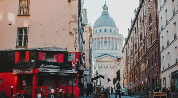 Urokliwa ulica w dzielnicy łacińskiej Paryża z czerwonym bistro i majestatycznym Panteonem w tle.