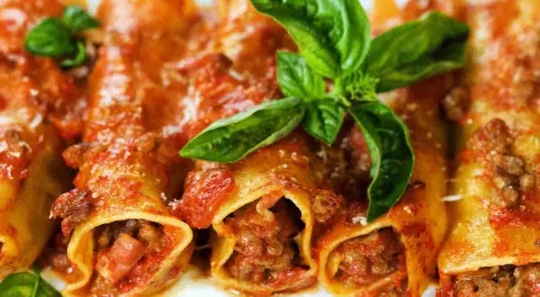 Cannelloni di carne ricetta della nonna, ripieni di ragù e conditi con sugo rosso e basilico fresco. Un piatto che sa di casa.