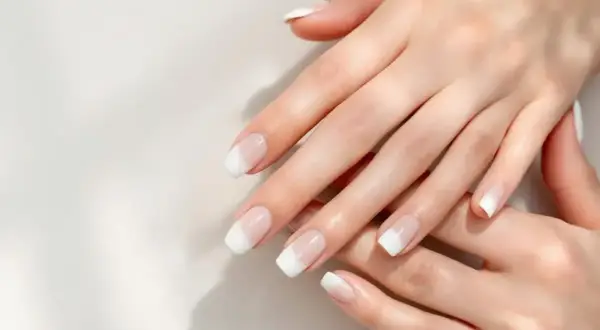 Mains délicates aux ongles parfaits, arborant une manucure blanche classique et élégante.