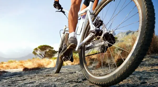 Rowerzysta na rowerze crossowym lub trekkingowym pokonuje kamienisty szlak.