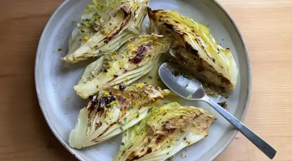 Grilla spetskål med citron och örter, serverad på en ljusgrå tallrik med en sked.