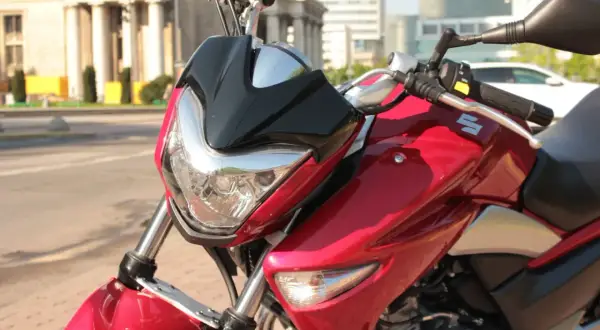 Błyszczący, czerwony motocykl Suzuki Inazuma z czarnym akcentem na przedniej owiewce, gotowy do jazdy po mieście.