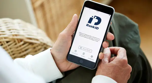 Person håller upp en telefon med BankID-appen öppen, redo för inloggning eller underskrift. Perfekt för din bankID ny telefon.